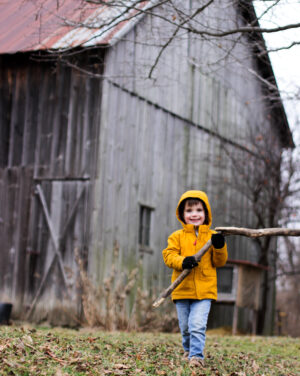 Boy playing on a farm in January with bare branches